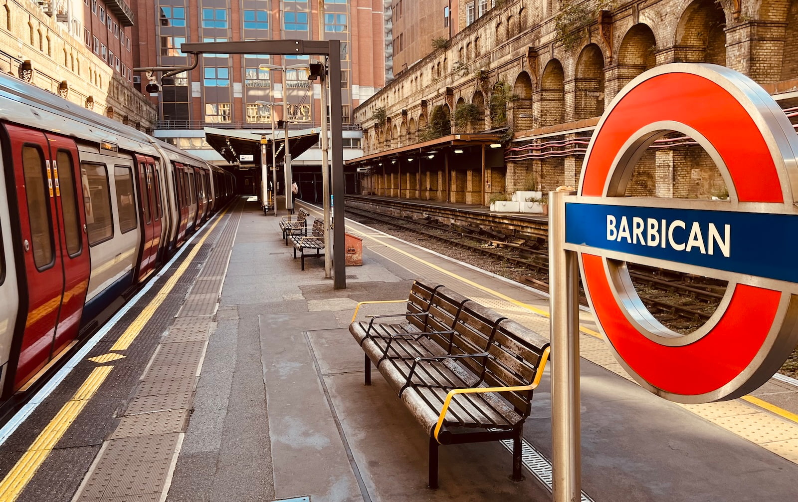 iconic london metro sign for barbican station with a tube on the left